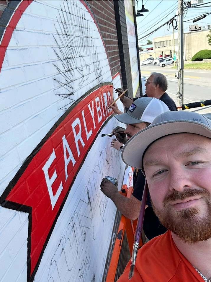 Sign painter working on large outdoor sign